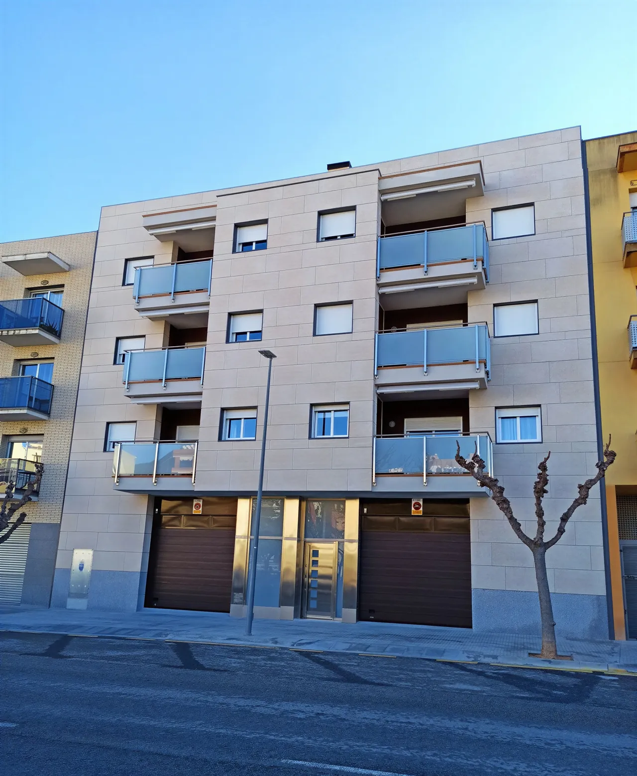 Edifici d'habitatges amb façana de peces en to sorra, vist des del carrer.